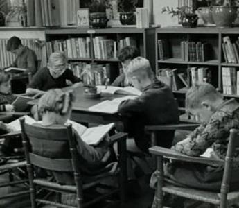 Kinderen lezen boek aan tafel in kinderleeszaal / jeugdbibliotheek. [1935].  fotograaf: Wiel van der Randen
