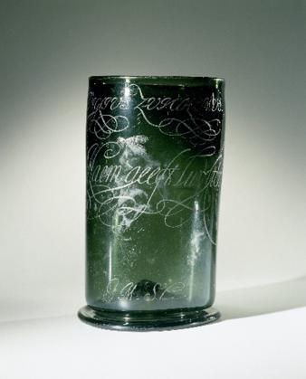 Een door Van Schurman gegraveerde beker. Het opschrift luidt: 'Al schyn ick duyster, De Naem geeft luyster’. Onderaan de handtekening 'A.M. à Schurman'.